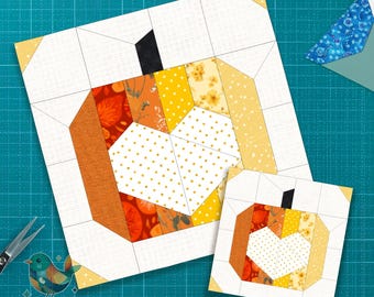 May include: Two pumpkin-themed quilt blocks. The larger block features a pumpkin design with orange, yellow, and white fabrics. The smaller block mirrors the design. The blocks are on a teal cutting mat. The text "Pattern by Kia" is visible.