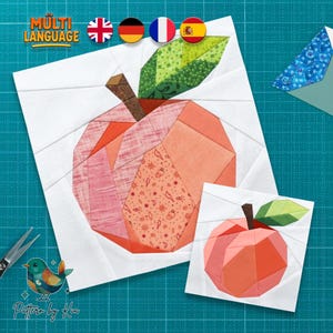 May include: Two fabric apple quilt blocks. The larger block features a peach-colored apple with a green leaf and brown stem. The smaller block is a simplified version of the apple. The words "MULTI LANGUAGE" are at the top left.