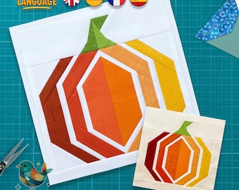 May include: A quilt block pattern featuring a stylised pumpkin design constructed from fabric strips in shades of dark red, orange, and yellow, with a green stem, set against a white background, accompanied by a smaller version of the same design.