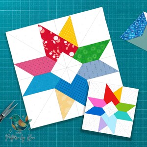 Pode incluir: Dois blocos de colcha de estrela coloridos em uma esteira de corte turquesa. O bloco maior apresenta pontas de estrela vermelhas, amarelas, verdes, azuis e rosas. O bloco menor tem um design semelhante. Tesouras e um envelope estampado também são visíveis. O texto "Pattern by Kia" está no canto inferior esquerdo.
