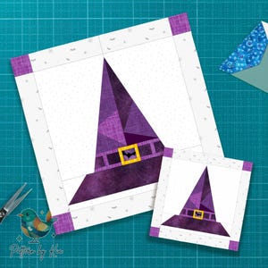 Puede incluir: Dos bloques de tela cuadrados con un diseño de sombrero de bruja morado, una hebilla amarilla y un detalle de murciélago. Los sombreros están sobre un fondo blanco con un patrón de puntos y un borde morado. También se ven unas tijeras y un logotipo de pájaro.