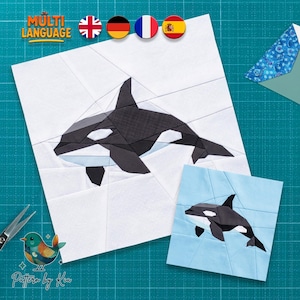 May include: A paper piecing quilt pattern featuring an orca whale design. The larger square shows a black and white orca on a white background, while the smaller square displays a black and white orca on a light blue background. The text reads MULTI LANGUAGE and Pattern by Kia.