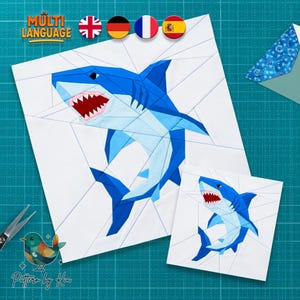 May include: Two white fabric squares with a geometric design of a blue shark with red teeth. The larger square has the text "MULTI LANGUAGE" and icons of flags. A pair of scissors and a bird logo are in the image.