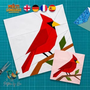 May include: A square quilt block pattern featuring a red cardinal bird perched on a brown branch against a white background, accompanied by a smaller version on a light pink background, with text reading MULTI LANGUAGE and Pattern by Kia.