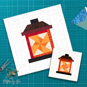 May include: Two quilt blocks featuring a lantern design. The larger block has a red, orange, brown, and black color scheme. The smaller block is a simplified version of the larger one. The background is white with a grid pattern.