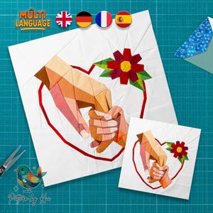 May include: Two white fabric squares with a heart and hands design. The larger square features a red heart outline, hands holding, and a red and yellow flower. The smaller square mirrors the design. The image includes the text "MULTI LANGUAGE" and "Pattern by Kiu".