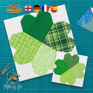 May include: Two fabric shamrock quilt blocks in shades of green and white. One large block features a plaid, leaf, and solid green design. A smaller block with a four-leaf clover design is also shown. The image includes the text "MULTI LANGUAGE" and "Pattern by Kia".