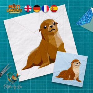 Op de afbeelding: Een quiltblokpatroon met een geometrisch zeeleeuwontwerp in bruin- en tinten. Het grotere blok heeft een witte achtergrond, terwijl het kleinere blok een lichtblauwe achtergrond heeft. De tekst "MULTI LANGUAGE" is bovenaan zichtbaar.