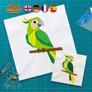 May include: Two white fabric squares with a geometric parrot design in shades of green, yellow, and gray perched on a brown branch. The design is repeated on a smaller square. The image includes the text "MULTI LANGUAGE" and a logo that says "Pattern by Kia".