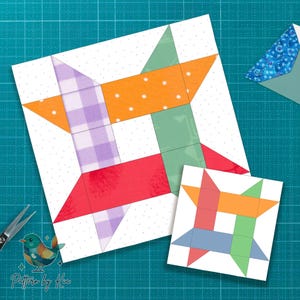 May include: Two colorful quilt block designs on a white background, one large and one small. The large block features red, orange, green, and purple fabric pieces. The small block has a similar design with different colors. A pair of scissors and a patterned envelope are also visible.