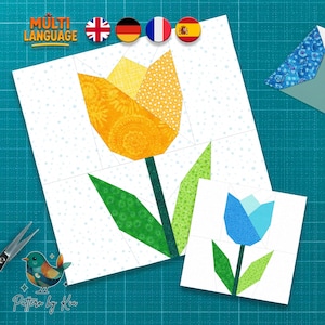 Puede incluir: Dos diseños de tulipanes de tela, uno grande y otro pequeño, sobre un fondo blanco. El tulipán grande es amarillo y el pequeño es azul. La imagen incluye el texto "MULTI LANGUAGE" y un logotipo que dice "Pattern by Kia".