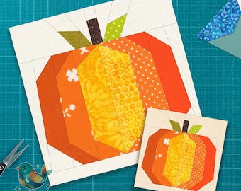 May include: Two paper pieced pumpkin blocks in shades of orange, yellow, and brown. The larger block is approximately 20 cm square, and the smaller one is about 10 cm square. The background is a light cream colour.