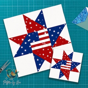 May include: Two star-shaped quilt blocks in red, white, and blue. The larger block features a star design with red and white stripes and blue sections with white stars. A smaller block mirrors the design. The blocks are on a blue cutting mat.