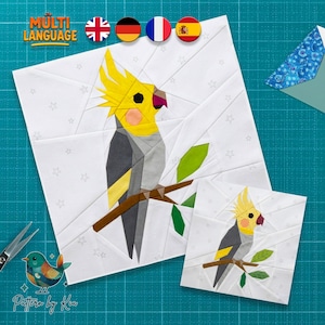 May include: Two white fabric squares with a geometric design of a cockatiel bird perched on a branch. The bird has yellow, gray, and pink coloring. The larger square is approximately 10 inches square, and the smaller square is approximately 5 inches square.
