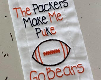 Può includere: Un canovaccio rettangolare bianco con testo ricamato in filo arancione e nero che recita The Packers Make Me Puke Go Bears. Sotto il testo si trova un pallone da football americano ricamato in filo arancione, nero e bianco con dettagli di cucitura.