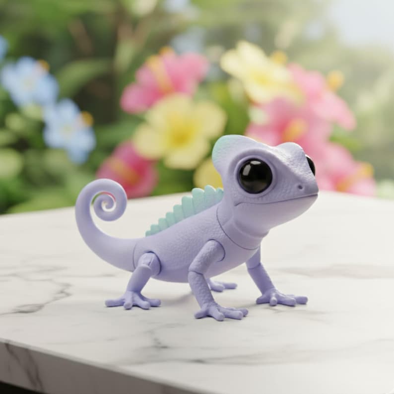May include: A lavender-colored toy chameleon with large black eyes and a curled tail. The toy has a light blue crest and accents. It is posed on a white marble surface with a blurred floral background.