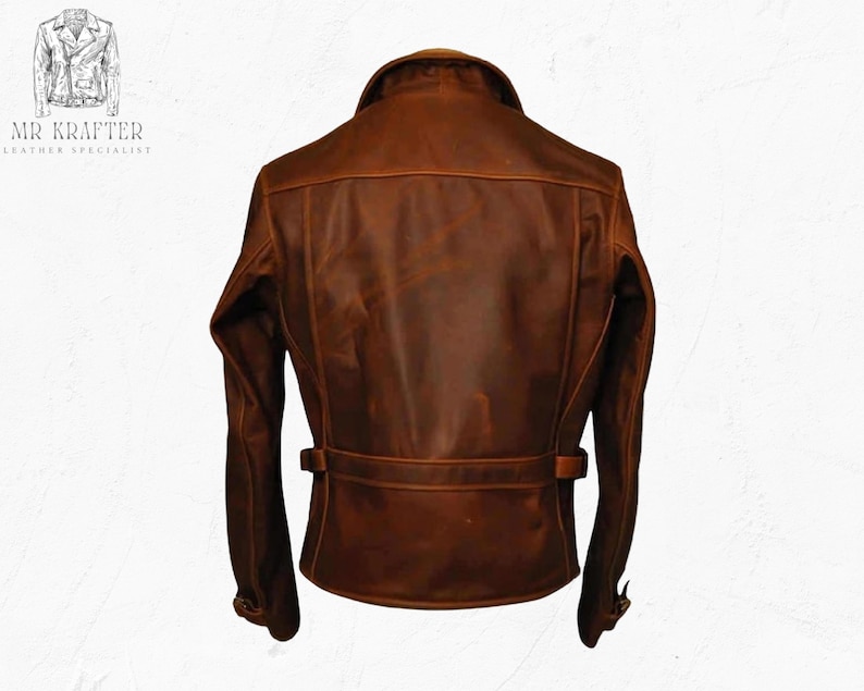 May include: A brown leather jacket with a classic design. The jacket features a collar, shoulder detailing, and a belt around the waist. The back of the jacket is visible, showcasing the stitching and texture of the leather. The jacket has a vintage, worn look.