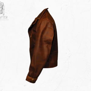 May include: A brown leather jacket with a classic design. The jacket features a notched collar, a zipper closure, and a belt detail at the waist. The image also shows the text "MR KRAFTER LEATHER SPECIALIST".