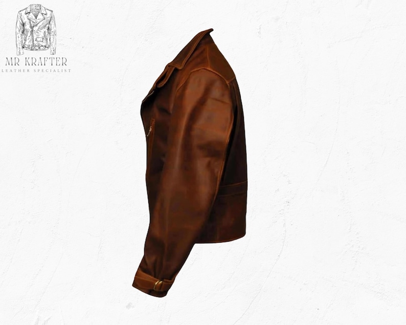 May include: A brown leather jacket with a classic design. The jacket features a notched collar, a zipper closure, and a belt detail at the waist. The image also shows the text "MR KRAFTER LEATHER SPECIALIST".