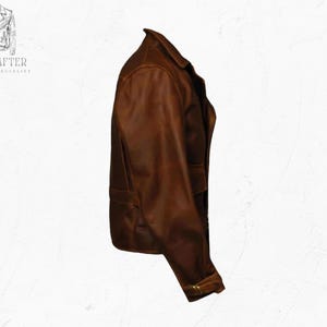 May include: A brown leather jacket with a classic design. The jacket features a notched collar, two front pockets, and a buttoned cuff. The jacket is made of a distressed leather material.