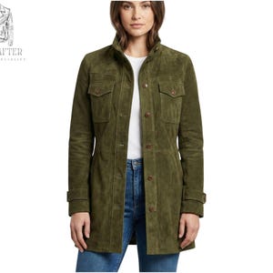 Puede incluir: Chaqueta de ante verde oliva con cierre de botones, dos bolsillos en el pecho y mangas largas. La chaqueta se lleva sobre una camiseta blanca y vaqueros azules. El logotipo de la marca "MR KRAFTER LEATHER SPECIALIST" está en la esquina superior izquierda.