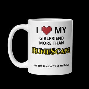 Pode incluir: Caneca de cerâmica branca com uma alça preta. A caneca apresenta o texto "I ❤️ MY GIRLFRIEND MORE THAN RUNESCAPE" em preto e amarelo, com um coração vermelho pixelado. A parte inferior da caneca diz "...YES SHE BOUGHT ME THIS MUG".