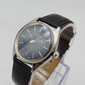 Puede incluir: Un reloj de pulsera plateado con esfera gris oscuro y correa de cuero negro. El reloj presenta marcadores de hora y agujas plateadas, y el nombre de la marca es visible en la esfera. La correa tiene un patr&oacute;n texturizado similar al de un cocodrilo.
