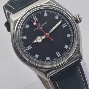 K&ouml;nnte beinhalten: Eine Edelstahl-Armbanduhr mit schwarzem Zifferblatt und schwarzem Lederarmband. Die Uhr hat wei&szlig;e Stundenmarkierungen, einen roten Sekundenzeiger und den Text "ULYSSES NARDIN SWISS MADE". Sie hat eine silberne L&uuml;nette und ein strukturiertes schwarzes Lederarmband.
