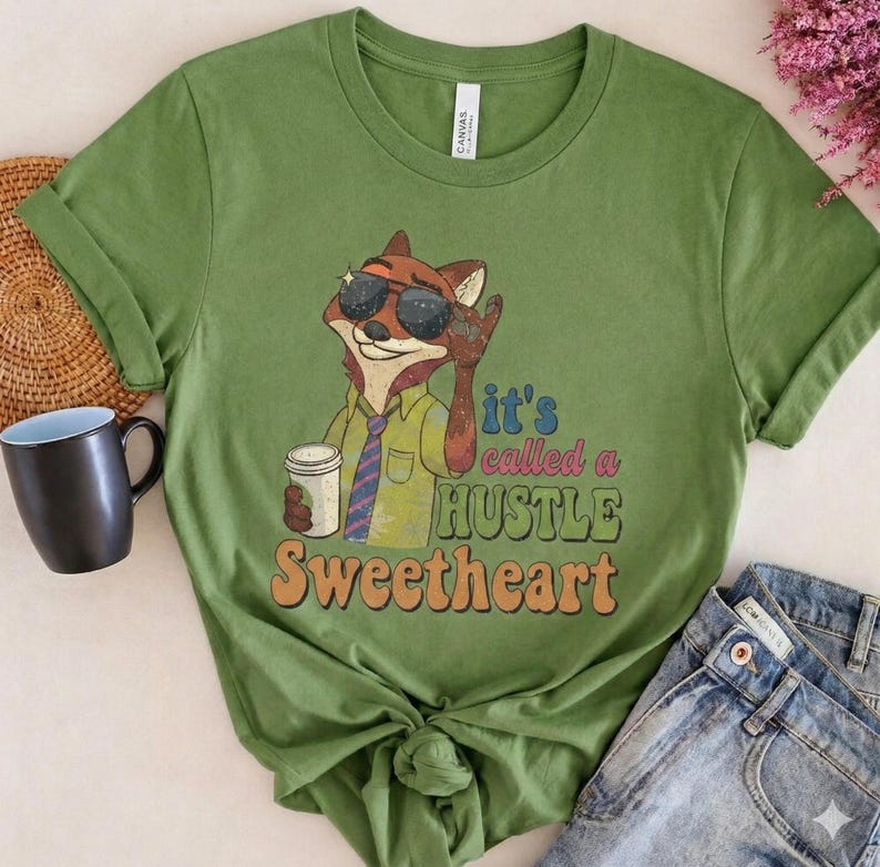 May include: Olive green t-shirt with a cartoon fox wearing sunglasses and holding a coffee cup. The shirt has the text "it's called a HUSTLE Sweetheart" in a retro font. The fox is wearing a shirt and tie.