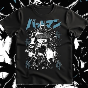May include: A black short-sleeved t-shirt featuring a graphic print of a comic book character in a spiked suit holding an axe. The design includes blue Japanese text at the top and blue stylised slash marks surrounding the figure, set against a black background.