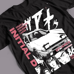 May include: A black t-shirt featuring a white graphic of a sports car, Japanese text, and the words INITIAL D, OSAKA SPRINTER TRUENO AE86, GT-APEX, and AKINA'S 86. The design includes pink accents and illustrations of human faces at the bottom.