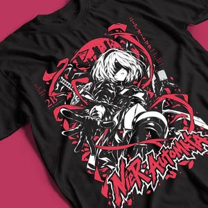 Könnte beinhalten: Ein schwarzes T-Shirt mit einem Grafikdruck der Figur 2B aus Nier: Automata. Das Design enthält rote und weiße Akzente, ein Schwert, fließende Bänder sowie den Text 2B, For the Glory of Mankind und Nier: Automata in stilisierten Schriftarten.