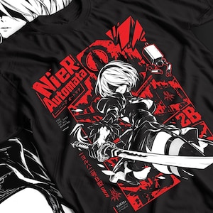 Könnte beinhalten: Ein schwarzes T-Shirt mit einem Grafikdruck der Figur 2B aus NieR: Automata. Das Design zeigt die Figur mit einem Schwert, rote geometrische Formen und den Text NieR Automata, 2B, YoRHa sowie For the sake of mankind.