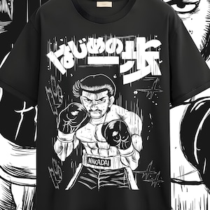 May include: Black t-shirt featuring a black and white illustration of a boxer with boxing gloves. The Japanese text is above the boxer. The boxer's name, Nakadai, is printed on his shorts.