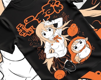 以下が含まれることがあります： 黒いTシャツ。アニメスタイルのイラストが特徴です。長い金髪、白いシャツ、黒いスカートの女性キャラクターが描かれています。オレンジ色の日本語のテキストと漫画のキャラクターも含まれています。