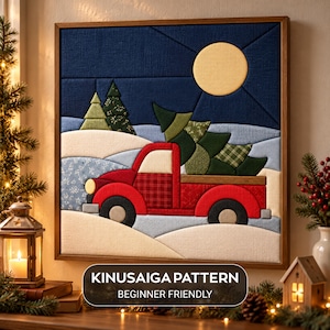 May include: A square fabric wall art piece featuring a Kinusaiga pattern of a red truck carrying a green pine tree through a snowy landscape under a yellow moon. The text KINUSAIGA PATTERN BEGINNER FRIENDLY is printed at the bottom.