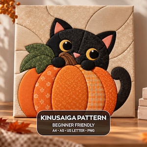 May include: A Kinusaiga fabric art piece featuring a black cat with large yellow eyes peeking over a bright orange pumpkin. The background is a light beige fabric with a subtle floral pattern. Text reads: KINUSAIGA PATTERN BEGINNER FRIENDLY A4 A5 US LETTER PNG.