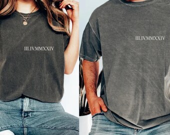 May include: Two gray t-shirts with the Roman numeral date III.IV.MMXXIV printed on the front. The shirts are worn with blue jeans. The t-shirts have a vintage, washed look.