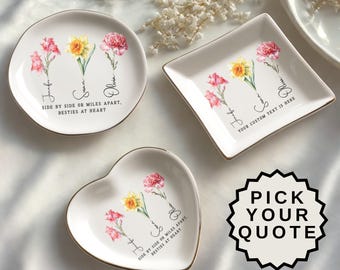 May include: A collection of personalized ceramic trinket dishes in round, square, and heart shapes. Each dish features floral designs with names and the text "SIDE BY SIDE OR MILES APART, BESTIES AT HEART" or "YOUR CUSTOM TEXT IS HERE". The dishes have gold rims.