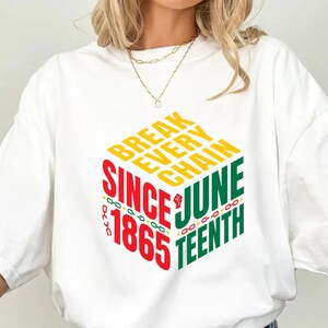 Może przedstawiać: Biała koszulka z kolorowym nadrukiem graficznym. Projekt zawiera słowa "BREAK EVERY CHAIN SINCE 1865 JUNE TEENTH" w kolorze czerwonym, ż&oacute;łtym i zielonym. Koszulka ma kr&oacute;tkie rękawy i okrągły dekolt.