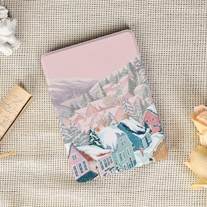 以下が含まれることがあります： 雪に覆われた家と常緑樹が描かれた、冬の村のシーンが特徴の長方形の薄いピンク色のケース。 アートワークは、雪景色を描いた、柔らかいパステルカラーパレットを使用しています。 このケースは、小さなアイテムを保管するためのものです。