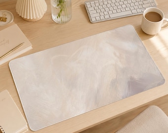 May include: A rectangular desk mat featuring a soft, abstract design with blended strokes of cream, off-white, and light gray. The surface has a smooth, matte texture with rounded corners, providing a neutral and subtle aesthetic for a workspace.