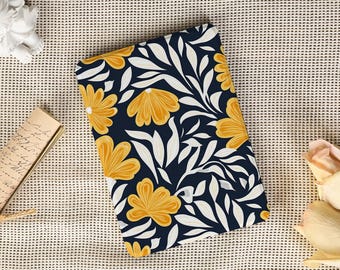 May include: A rectangular, floral-patterned item featuring a navy blue background with yellow flowers and white leaves. The design is symmetrical and covers the entire surface. The item is lying on a textured, beige surface.