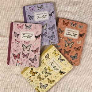 May include: Four composition books with butterfly patterns in lavender, pink, orange, and yellow. Each book features a central white label with the text "COMPOSITION BOOK Jaco Gift" and a dark spine. The covers are decorated with various butterfly illustrations.