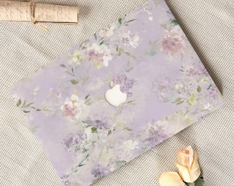 May include: A lavender laptop case with a floral design featuring white, purple, and green flowers. The case has a cutout for the Apple logo. The floral pattern covers the entire surface of the case.