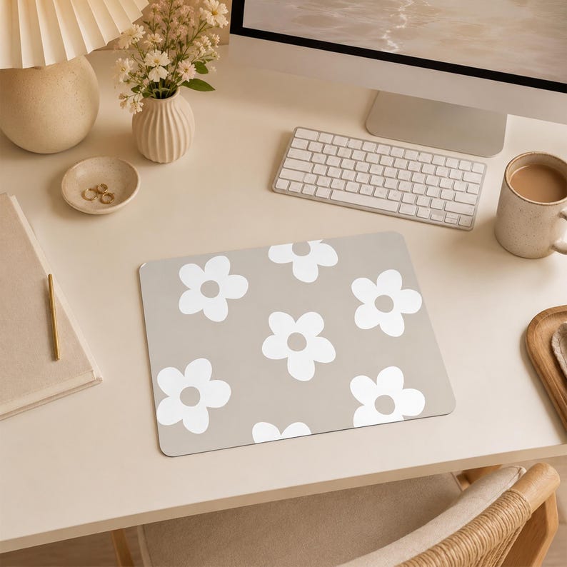 Puede incluir: Una alfombrilla de rat&oacute;n rectangular con un fondo de color beige claro y un patr&oacute;n repetitivo de flores blancas de cinco p&eacute;talos. Las flores est&aacute;n distribuidas uniformemente por la superficie, creando un dise&ntilde;o gr&aacute;fico sencillo y coherente.