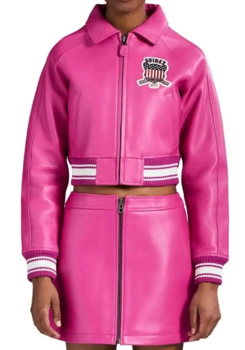 Puede incluir: Conjunto de chaqueta y falda de cuero rosa brillante. La chaqueta tiene cuello, cierre de cremallera y un parche en el pecho. Los pu&ntilde;os y el dobladillo de la chaqueta y la falda tienen detalles a rayas blancas y rosas. La falda tiene cremallera frontal.