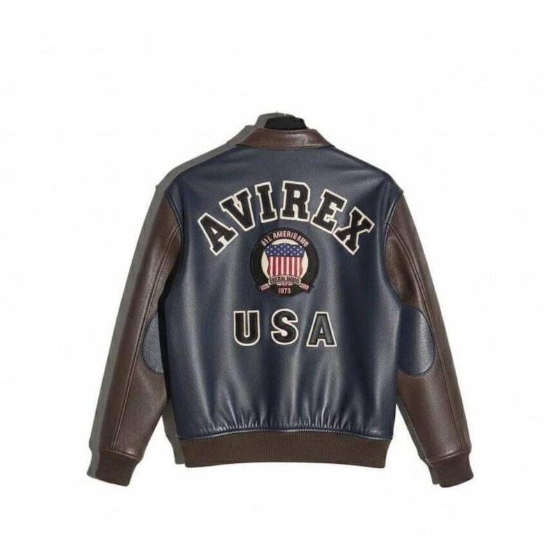 May include: A navy blue and brown leather jacket with the word "AVIREX" in white lettering across the back. Below the word "AVIREX" is a patch with the American flag and the word "USA". The jacket has brown sleeves and a brown collar.