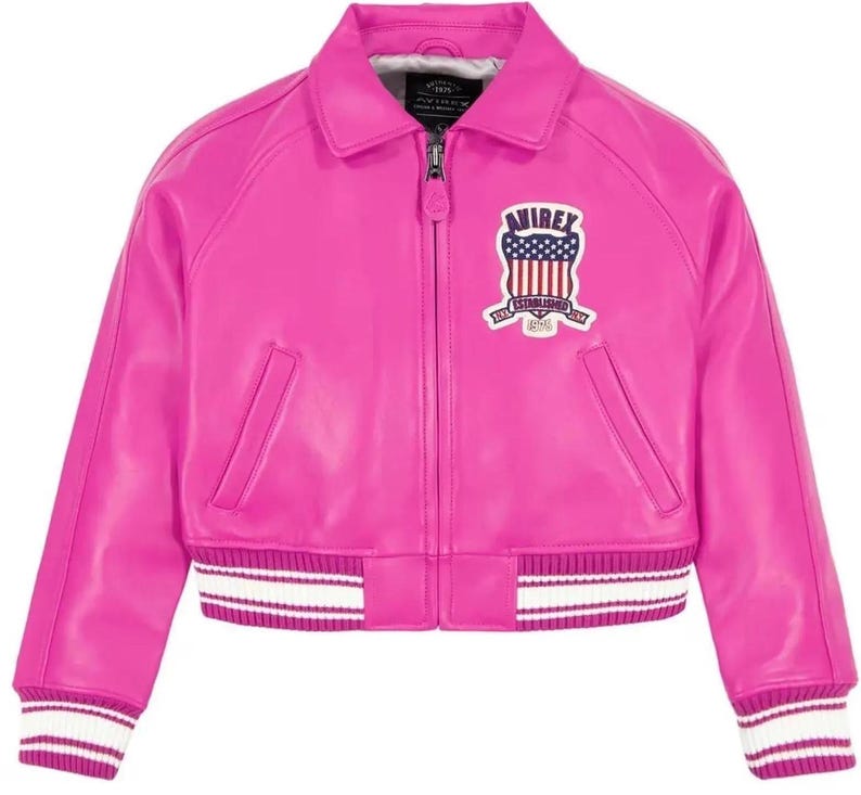 Puede incluir: Chaqueta bomber de cuero rosa brillante. Presenta un cuello cl&aacute;sico, cierre de cremallera y pu&ntilde;os y dobladillo a rayas blancas y rosas. Un parche bordado con el texto "AVIREX" y un dise&ntilde;o patri&oacute;tico adorna el pecho.