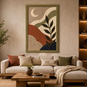 Op de afbeelding: Een rechthoekig getuft wandkleed met een abstract landschapsontwerp met een halve maan, glooiende heuvels in tinten terracotta, olijfgroen, crème en donkerblauw, en een opvallende bladerige tak, omlijst door een textuurrijke olijfgroene rand.